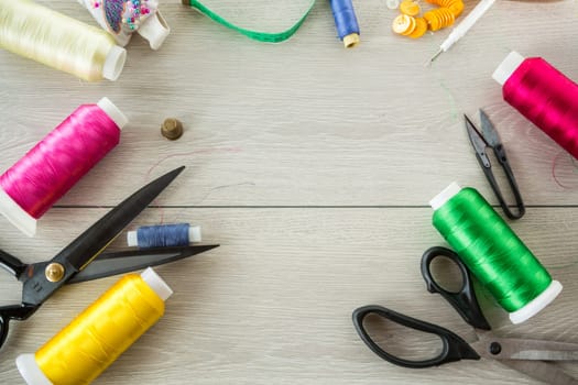 a set of tools and threads for sewing clothes, on a wooden background.