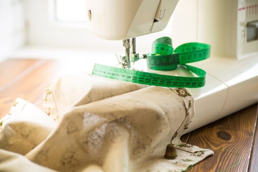 Sewing machine with fabric and threads for sewing, close-up. The working process. Part of a sewing machine with fabric.