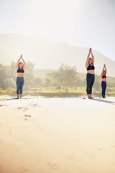 No one ever regretted a yoga session. three young women practicing yoga on the beach