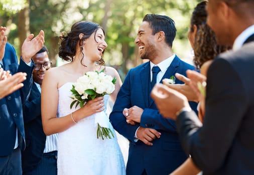 Wedding ceremony, couple and people clapping hands in celebration of love, romance and union. Happy, smile and bride with bouquet and groom walking by guests cheering for marriage at an outdoor event.