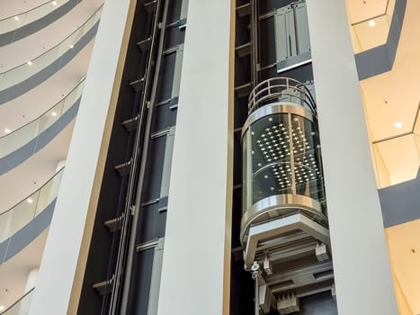 glass capsule elevator with people or tourist in the lift on vintage wall in the hall at luxury hotel or building
