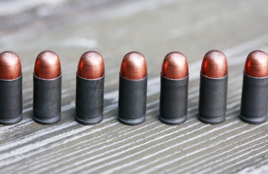 Closeup of few pistol bullets in a row on old wooden background