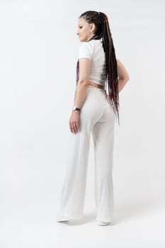 Fashionable young beautiful woman . Slim girl with dreadlocks in an active pose in a white pants and top . Fashion, clothing and style.