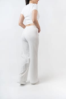 Fashionable young beautiful woman . Slim girl with dreadlocks in an active pose in a white pants and top . Fashion, clothing and style.