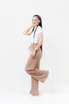 Fashionable young beautiful woman . Slim girl with dreadlocks in an active pose in a white pants and top . Fashion, clothing and style.