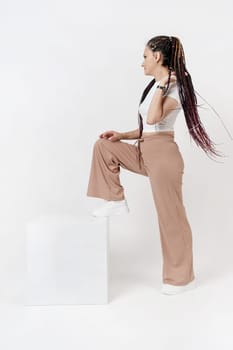 Fashionable young beautiful woman . Slim girl with dreadlocks in an active pose in a white pants and top . Fashion, clothing and style.