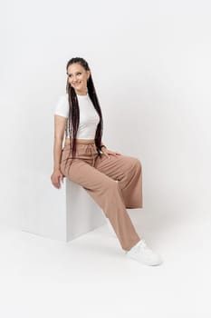 Fashionable young beautiful woman . Slim girl with dreadlocks in an active pose in a white pants and top . Fashion, clothing and style.