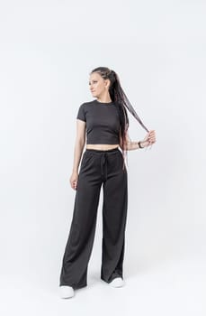 Fashionable young beautiful woman . Slim girl with dreadlocks in an active pose in black pants and top . Fashion, clothing and style.