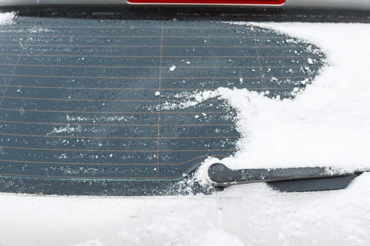 A snow-covered car stands on the street in winter. Snow on car windows