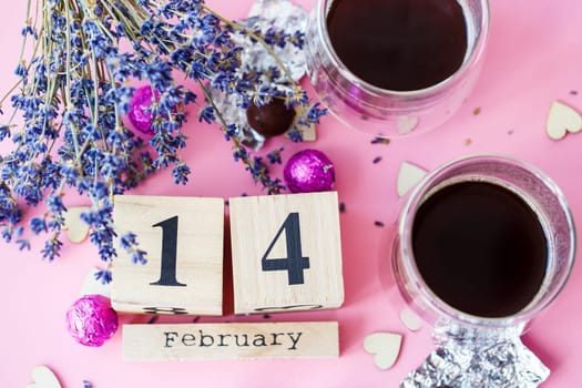 World Valentine's Day. Wooden calendar with date 14 February on pink background with coffee and sweets