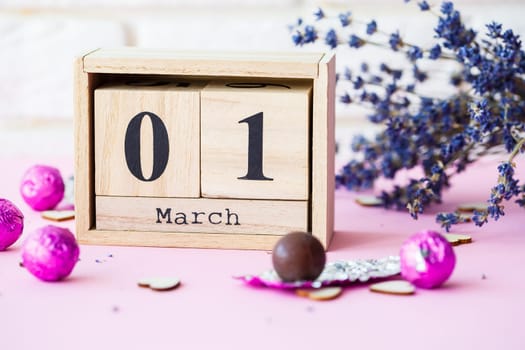 Wooden calendar with the date of March 1 on a pink background, a place for an inscription, The first day of spring, a dry branch of lavender