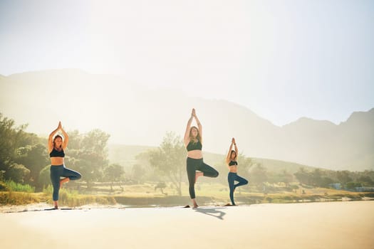 Yoga has unlimited benefits. three young women practicing yoga on the beach