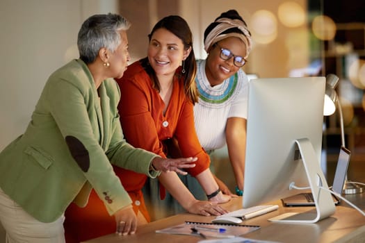 Collaboration, communication and a business woman with her team, working on a computer in the office at night. Teamwork, diversity and coaching with a senior female manager training her staff at work.