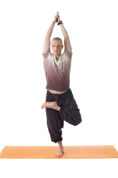 Smiling yogi posing standing on one leg, isolated over white background