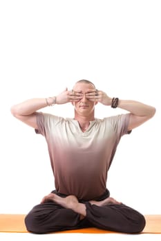 Man posing in lotus position, eyes closed with his hands