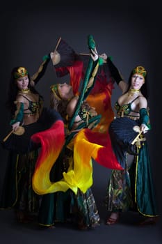 Graceful belly dancers posing with colorful fans in studio