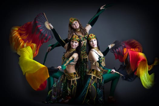 Trio of charming oriental dance performers posing in studio