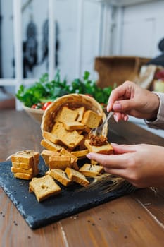 Slices of toasted bread and pate in female hands. Fresh croutons made of whole grain flour