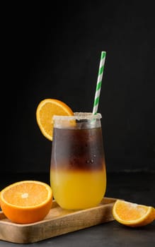 Iced coffee with orange juice in a transparent glass, refreshing bumble coffee on the table