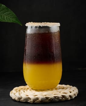 Iced coffee with orange juice in a transparent glass, refreshing bumble coffee on the table, black background