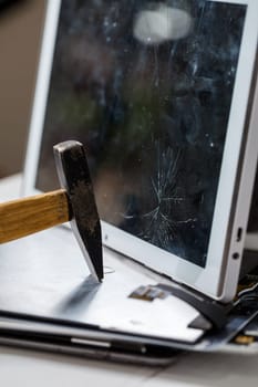 The hammer hits the broken touchscreen tablet, suggesting that it is about to replace it. Broken glass tablet repair