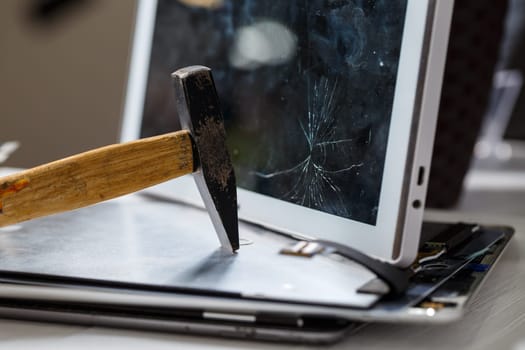 The hammer hits the broken touchscreen tablet, suggesting that it is about to replace it. Broken glass tablet repair