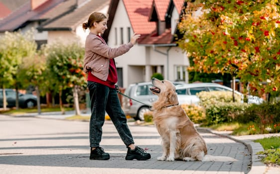 Preteen girl training his golden retriever dog . Female child kid with a purebred labrador doggy pet