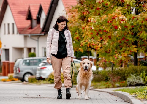 Preteen girl wear on golden retriever dog lace outdoors. Pretty woman with purebred pet doggy walking at autumn street