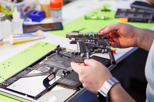Professional computer and tablet repair shop or service. Close up of a computer board. Electronics concept. Detail from a laptop under repair