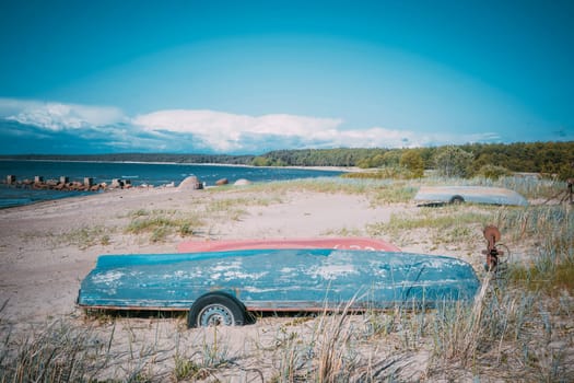 Old fishing boats pulled out on the sandy shore of the sea bay in sunny weather. Fishermen's boats are resting on the shore lying upside down