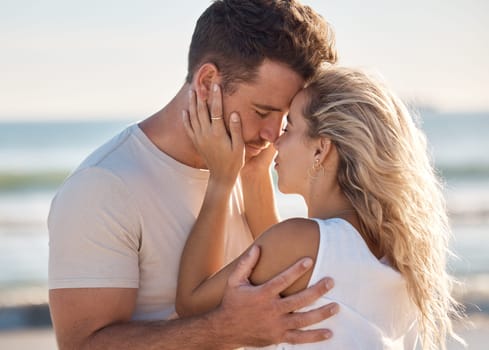 Love, kiss and beach with a young couple sharing an intimate moment on the coast by the sea or ocean. Nature, romance and travel with a man and woman bonding together on an outdoor date in summer.