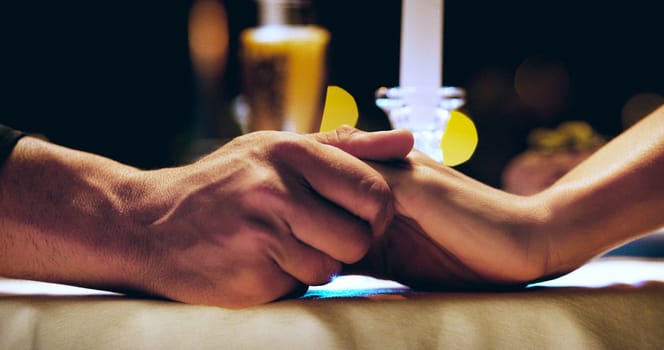 Holding hands, candle and couple on dinner date at restaurant, hotel or love on marriage anniversary celebration. Man, woman and fine dining together, trust and romance at night with hand closeup.
