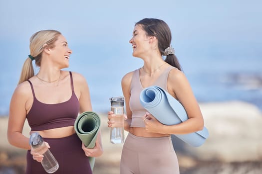 Women friends, fitness and water at beach while talking, happy and together for exercise. Happy people outdoor on blue sky for funny communication, motivation and laughing for morning workout bottle.