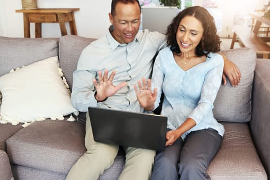 Laptop, couple and hello for video call on home sofa for communication and network connection. Man and woman wave hand for virtual conversation technology and distance family chat on lounge couch.