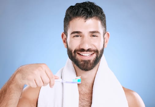 Toothbrush, portrait and man cleaning in studio for dental wellness, healthy smile and mouth. Happy male model brushing teeth, face and care of fresh breath, oral gums or dentistry on blue background.