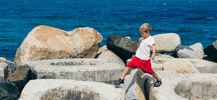 Real photo affirmation Every day brings me closer to my goal. boy child takes a wide step jumps steps over concrete blocks sea background summer sun.