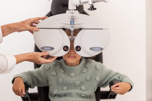 Girl, Ophthalmologist and eye test in an exam in clinic for medical check. Female optician or optometrist expert checking vision of a child examination equipment inside an optometry room at hospital.