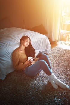 Time to unwind and enjoy the laze. a relaxed young woman drinking coffee and using a digital tablet at home