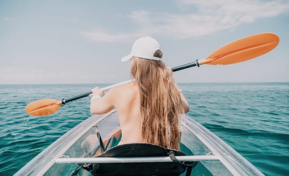 Woman in kayak back view. Happy young woman with long hair floating in transparent kayak on the crystal clear sea. Summer holiday vacation and cheerful female people having fun on the boat.