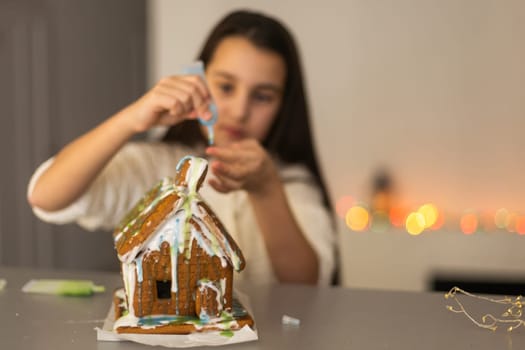 Kids baking Christmas gingerbread house. Children celebrating winter holiday at home. Decorated living room with fireplace and tree. Family activity. Little girl making cookies.