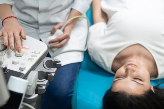 Doctor using ultrasound scanning machine for examining a thyroid of woman