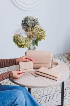 A beautiful woman holds a beige leather purse in her hands. Small women's handbag