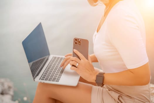 Freelance close up woman hands writing on computer. Well looking middle aged woman typing on laptop keyboard outdoors with beautiful sea view