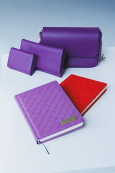 A leather wallet and a notebook lie on the table. Small women's handbag