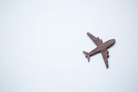A wooden airplane figurine is glued to a wall on a white background, a place for advertising text inscription