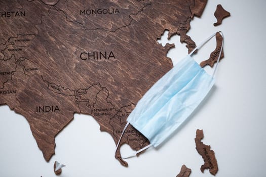 wooden map on a white background with a medical mask for protection against the virus