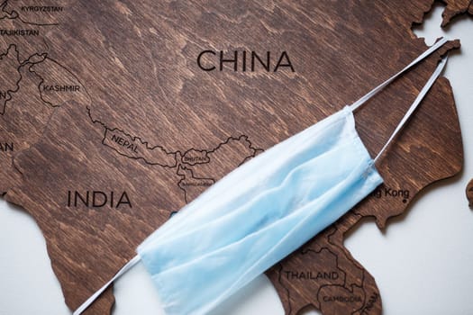 wooden map on a white background with a medical mask for protection against the virus