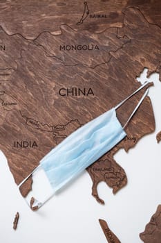 wooden map on a white background with a medical mask for protection against the virus