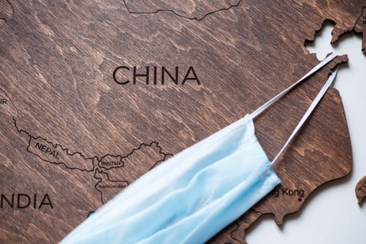 wooden map on a white background with a medical mask for protection against the virus