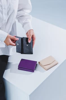 A stylish woman holds a black leather purse in her hands. Small women's handbag